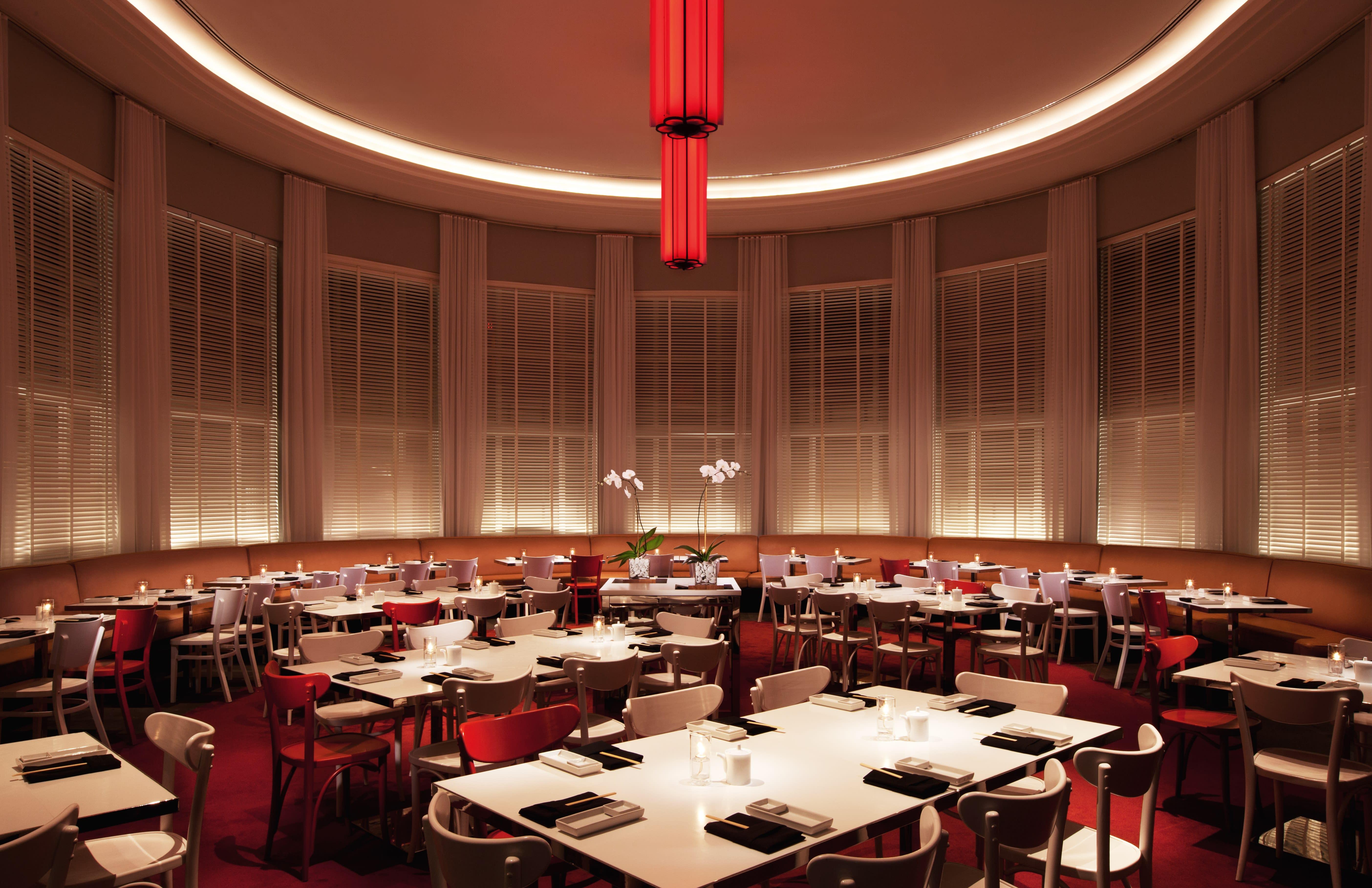 tables d'événement larges dans une salle circulaire avec tapis rouge et chandelier rouge 
