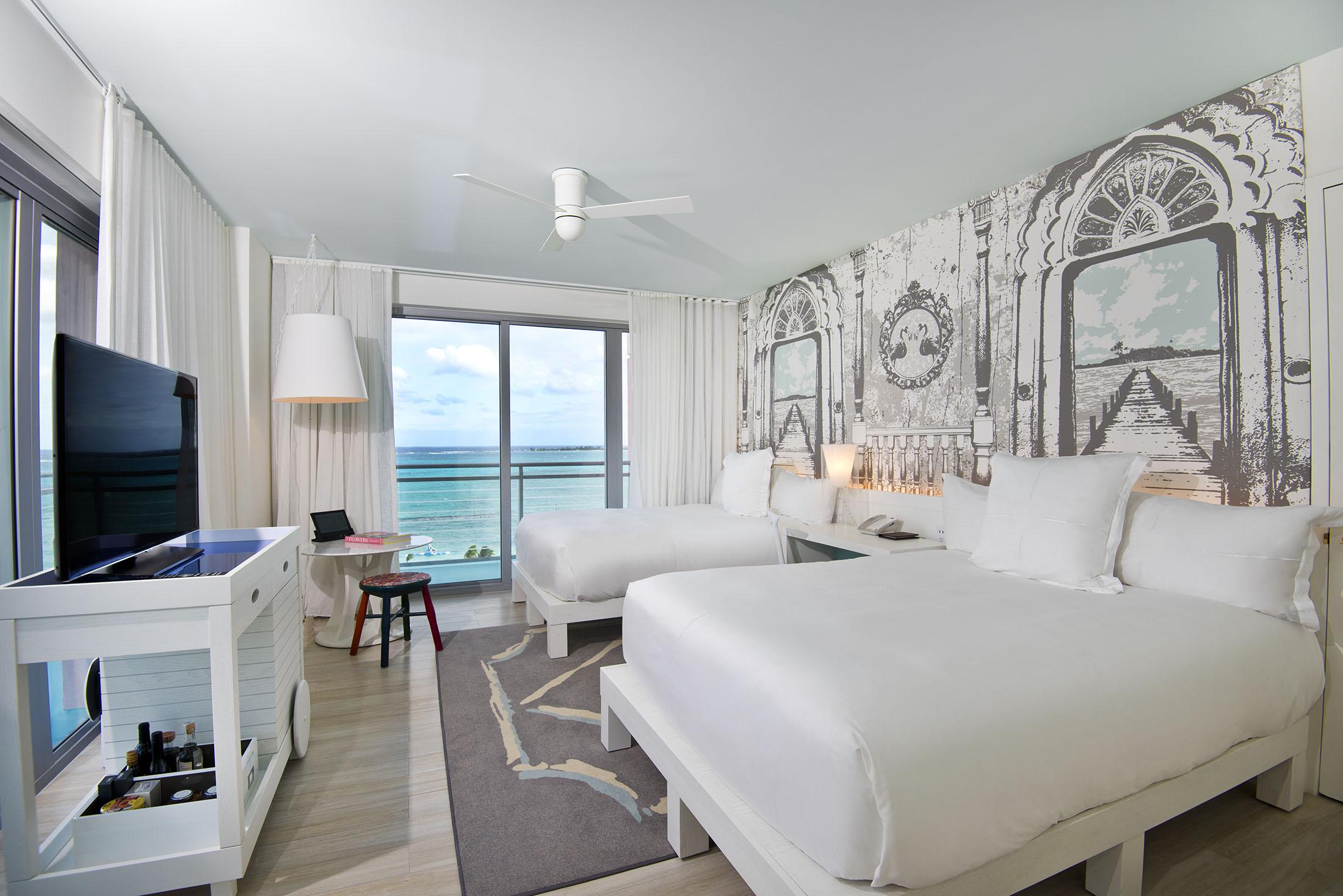 Une chambre d'hôtel avec deux lits et une baie vitrée donnant sur l'océan.